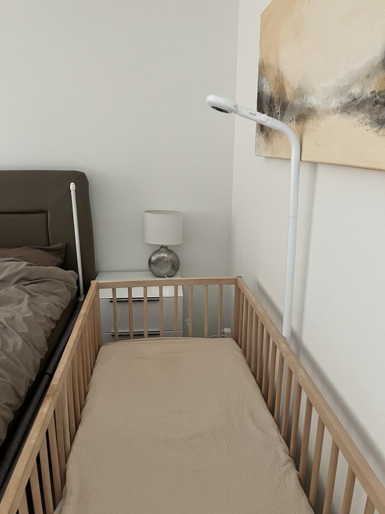 Nanit Pro Babyphone mit Bodenständer neben dem Babybett